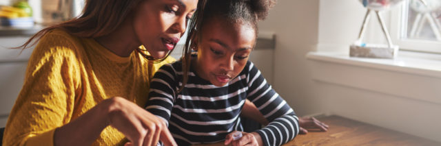 African-American mother helping daughter learn to write.