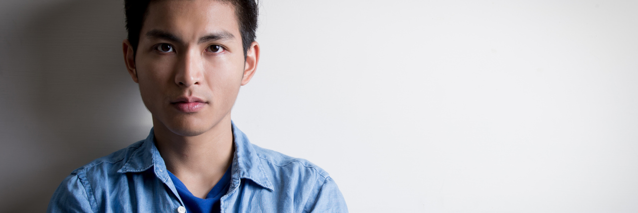 close up portrait photo of young asian man with arms folded looking into camera