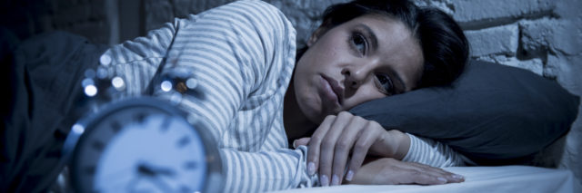 Woman in bed struggling with insomnia.