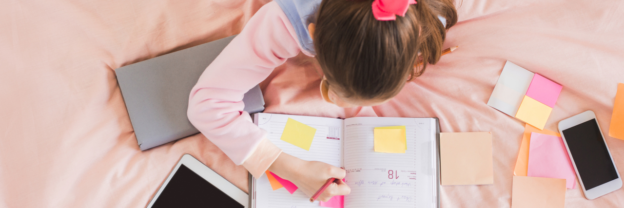 Addressing Executive Dysfunction in Autistic Children Girl writing in calendar planner.