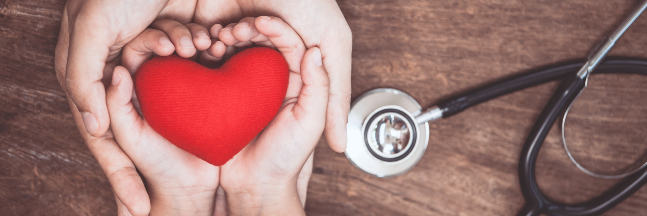 Finding a Doctor for Your Child With DYRK1A Syndrome woman and child's hands holding a heart, with a stethoscope next to their hands