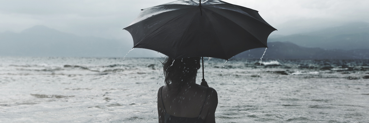 A Metaphor for Grief: Why Grief Is Like a Monsoon Woman with umbrella in the ocean