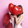 Couple kissing behind heart-shaped balloons