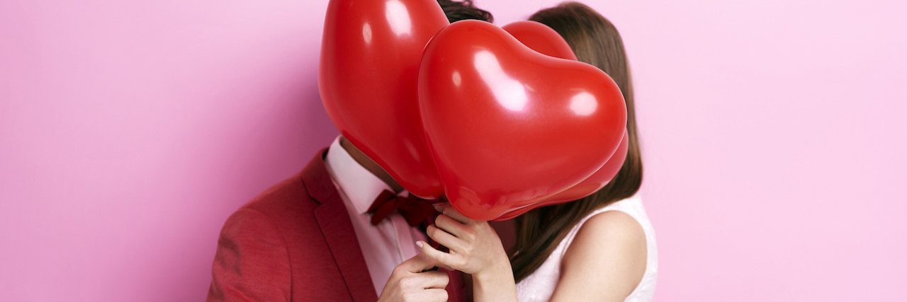 What I've Learned About Love and Mental Illness Couple kissing behind heart-shaped balloons
