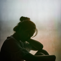 Silhouette of a sad woman sitting by a window.