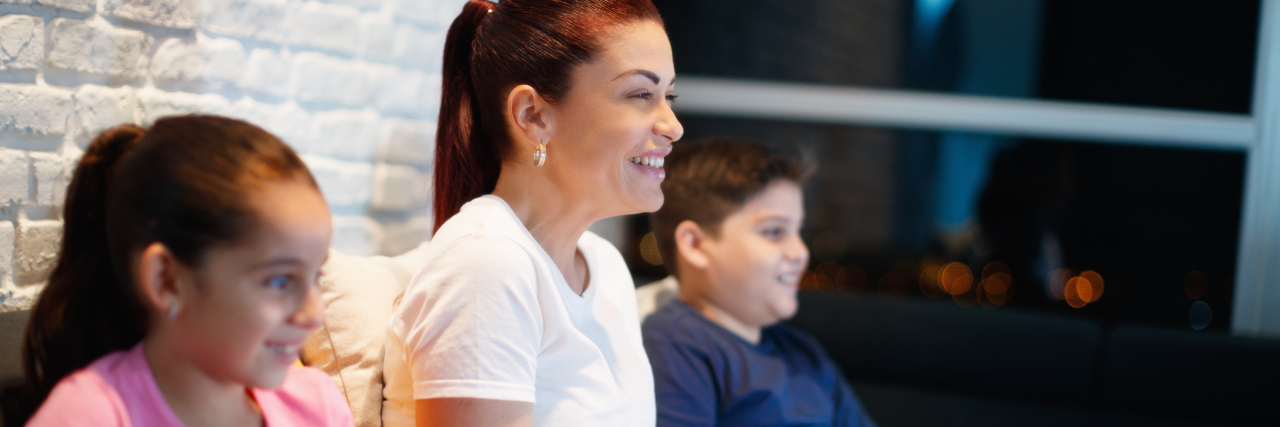 I'm a Disabled Mom, But I Am 'Enough' for My Kids a mom is watching a movie at home with her two kids