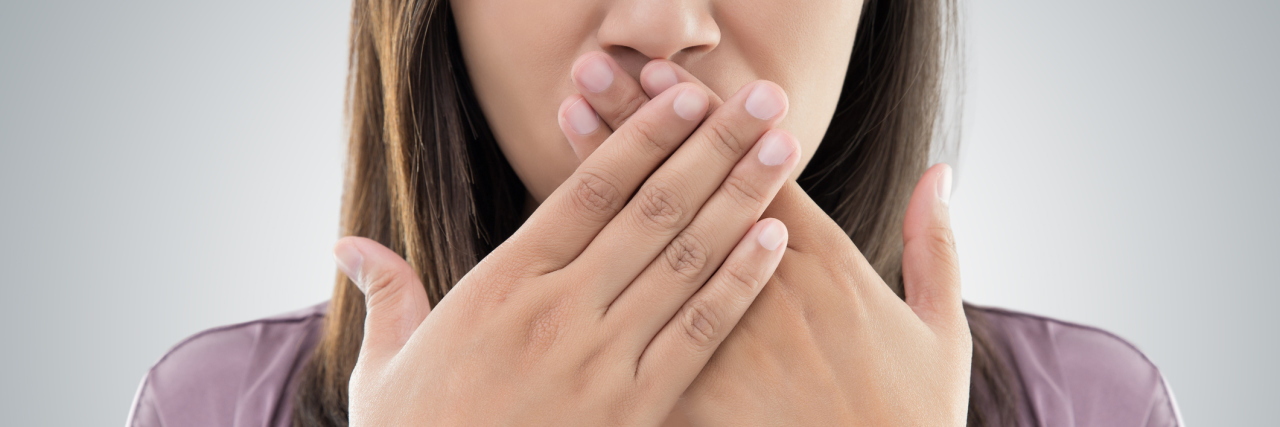 Why You Sometimes Have Trouble Speaking With Fibromyalgia woman with hands crossed and covering mouth