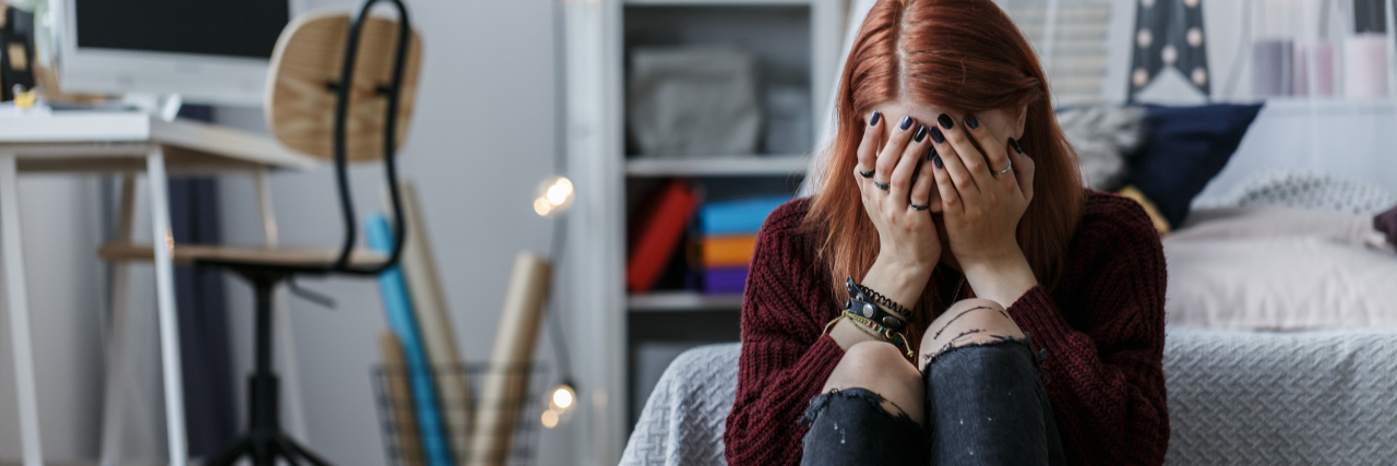 Things I Say as a Depressed Teen That Mean 'I'm Having a Bad Day' A girl sitting on the floor and crying with her hands over her face.