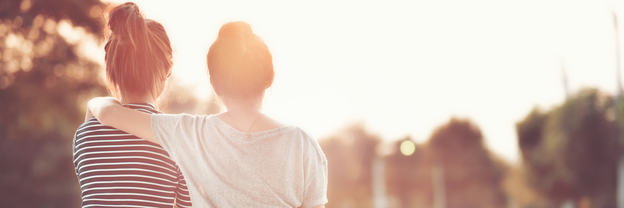 7 Ways To Support a Friend With OCD Two women friends are sitting next to each other at a park.