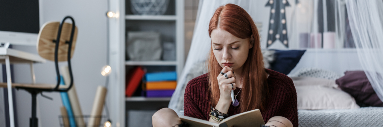 5 Reasons You Should Talk About Your Feelings Cogitative, redhead girl thinking over a notebook while sitting on a floor in her room