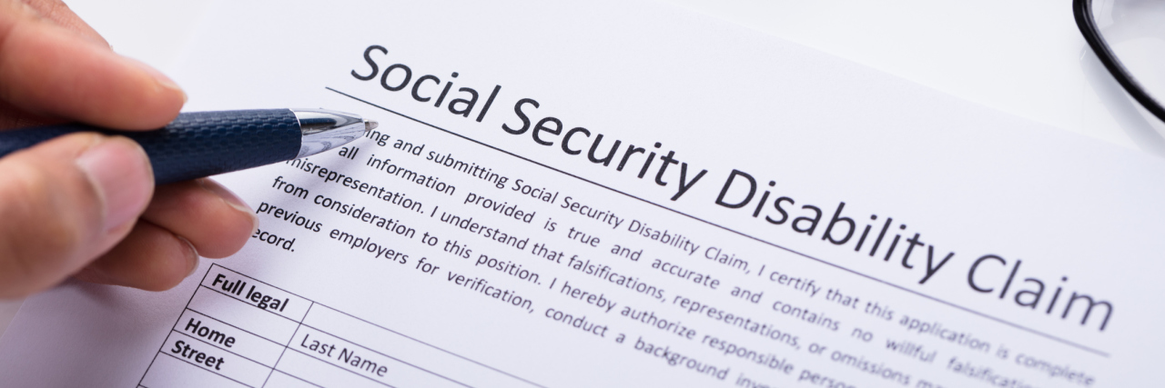 person holding a pen over a form for social security disability claim