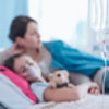A blurred photo of a child in a hospital bed with a mom sitting beside.