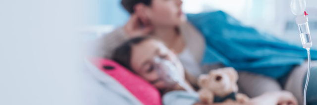 A blurred photo of a child in a hospital bed with a mom sitting beside.