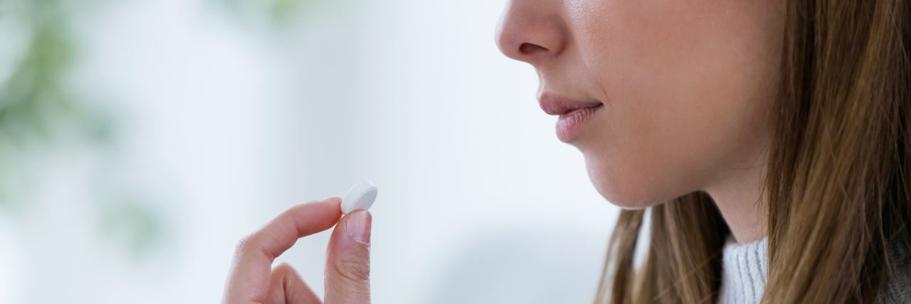 Stopping Mental Health Medication for Your Appearance photo of young woman with a glass of water and white pill