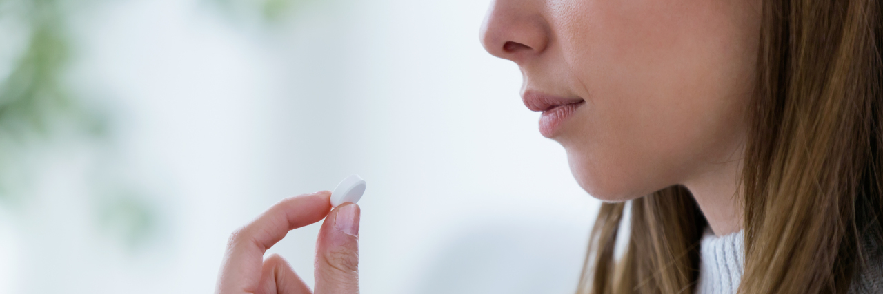 photo of young woman with a glass of water and white pill