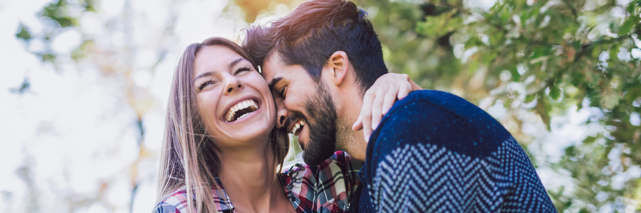 5 Tips for Managing Anxiety When You're in a Relationship A couple smiling and holding each other while outside
