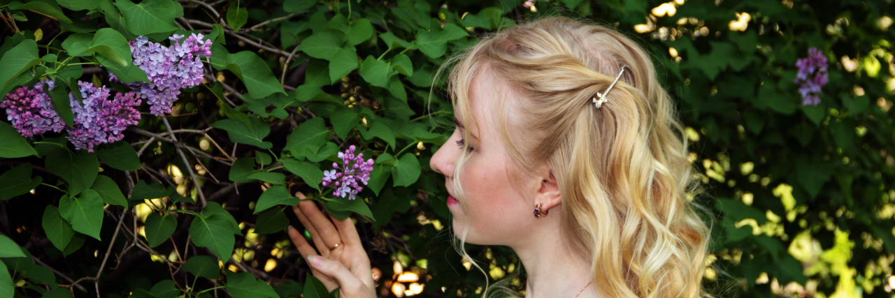 Struggling With Survivor's Guilt After Traumatic Brain Injury Woman admires lilac flowers.