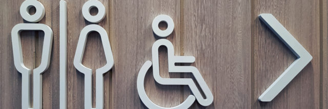 White disabled restroom symbols on wooden door.