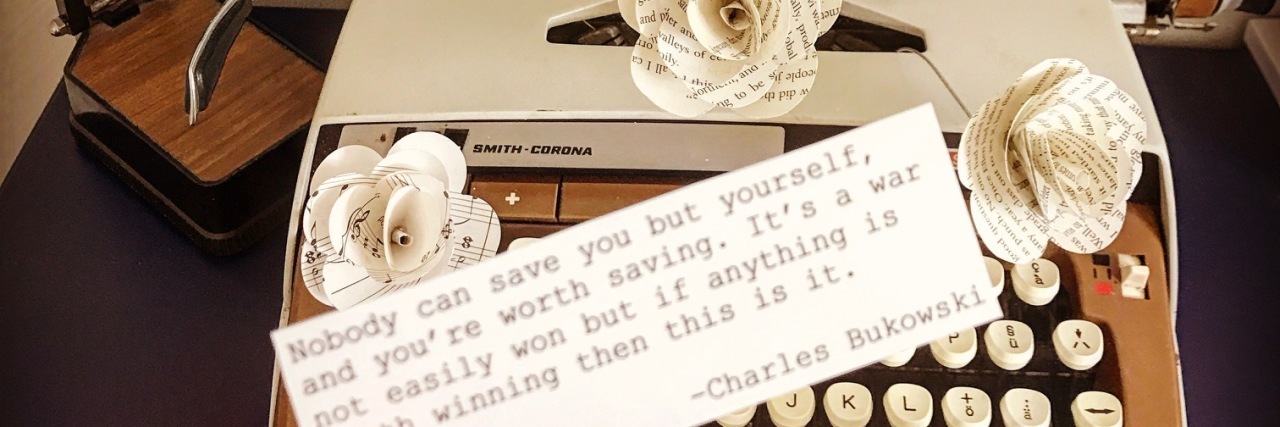 Hand holds inspirational quote over background of a white typewriter