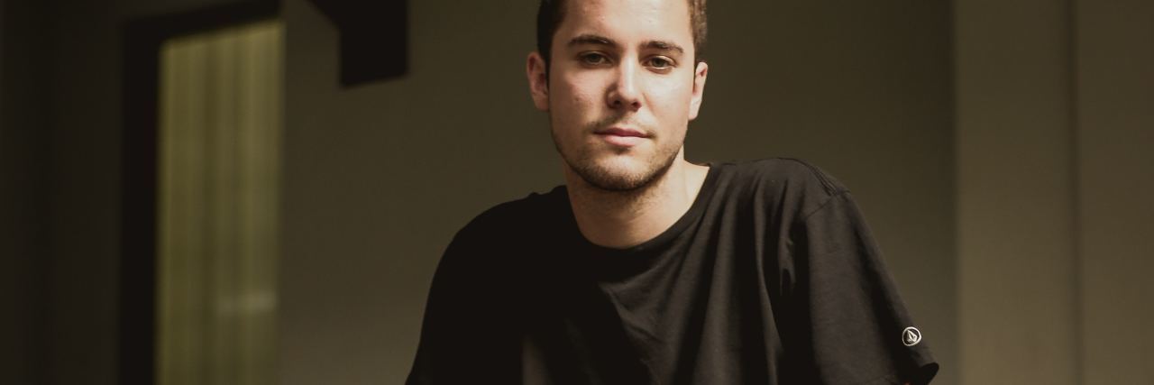 Why I Hide My Multiple Sclerosis Symptoms From People in ‘Real Life’ photo of young man sitting on wall wearing shorts and looking at camera