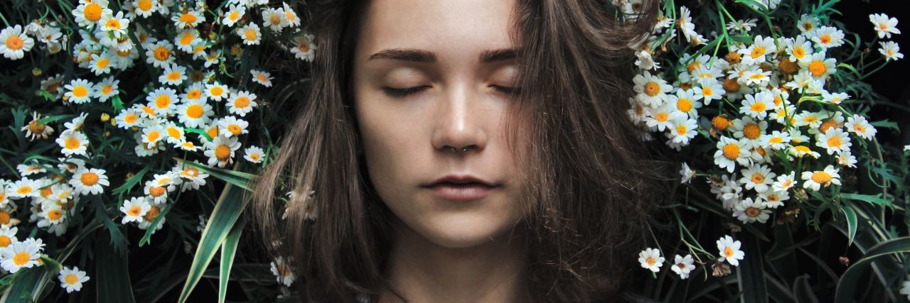 Feeling Like I'm Missing Out on Life Because of Chronic Fatigue photo of woman with closed eyes standing in front of white flowers
