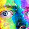 close up photo of person's face and eyes with rainbow face paint