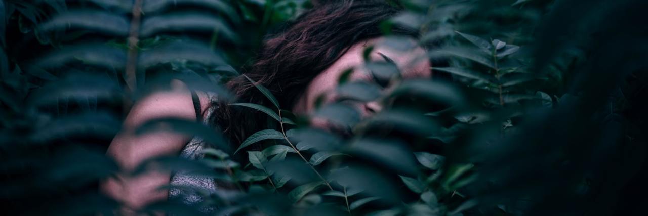photo of sleeping woman partially hidden by fern leaves