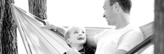 black and white photo of father and son on hammock looking at each other