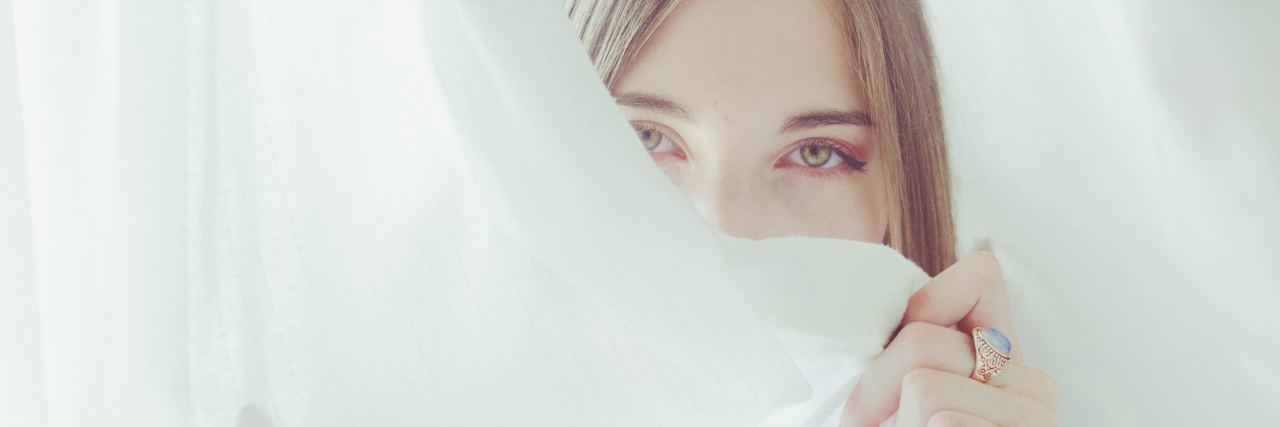 Borderline Personality Disorder Stigma as a Mental Health Professional photo of woman partially hiding face with white curtain looking into camera