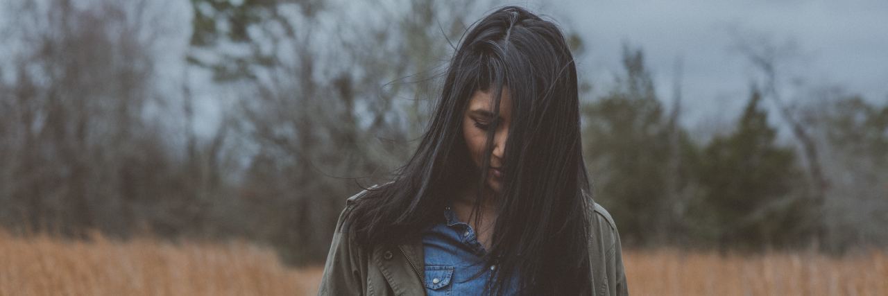 Struggling to Accept My Depression Diagnosis close up photo of woman in field with stormy sky looking down