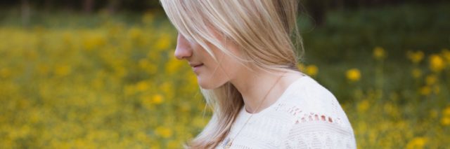 photo of blonde woman in profile view in meadow with yellow flowers and smiling
