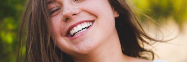 close up photo of woman smiling wide with eyes closed