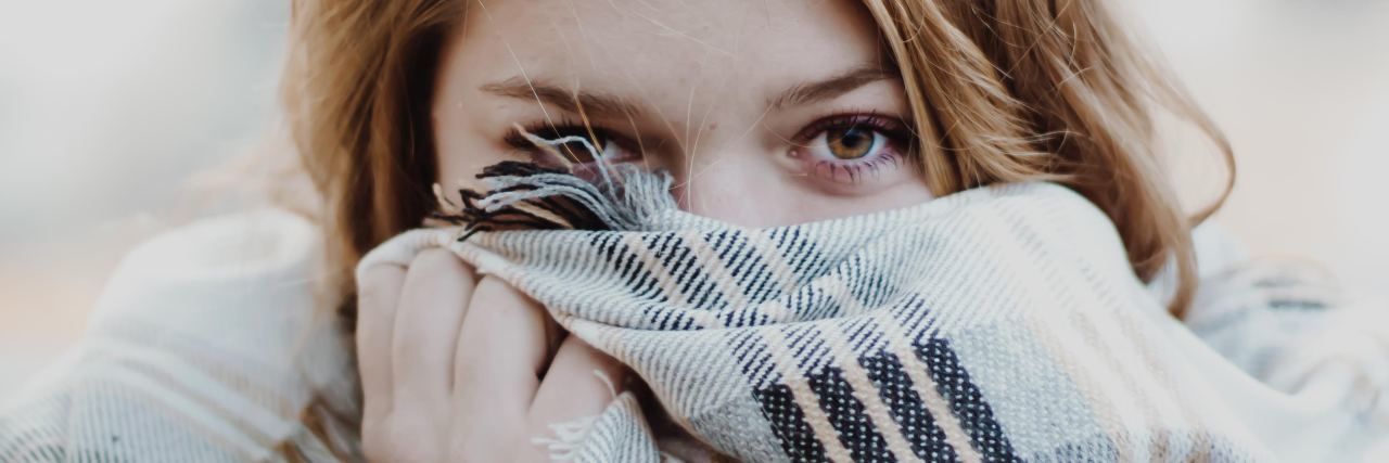 photo of young blonde woman covering part of face with scarf