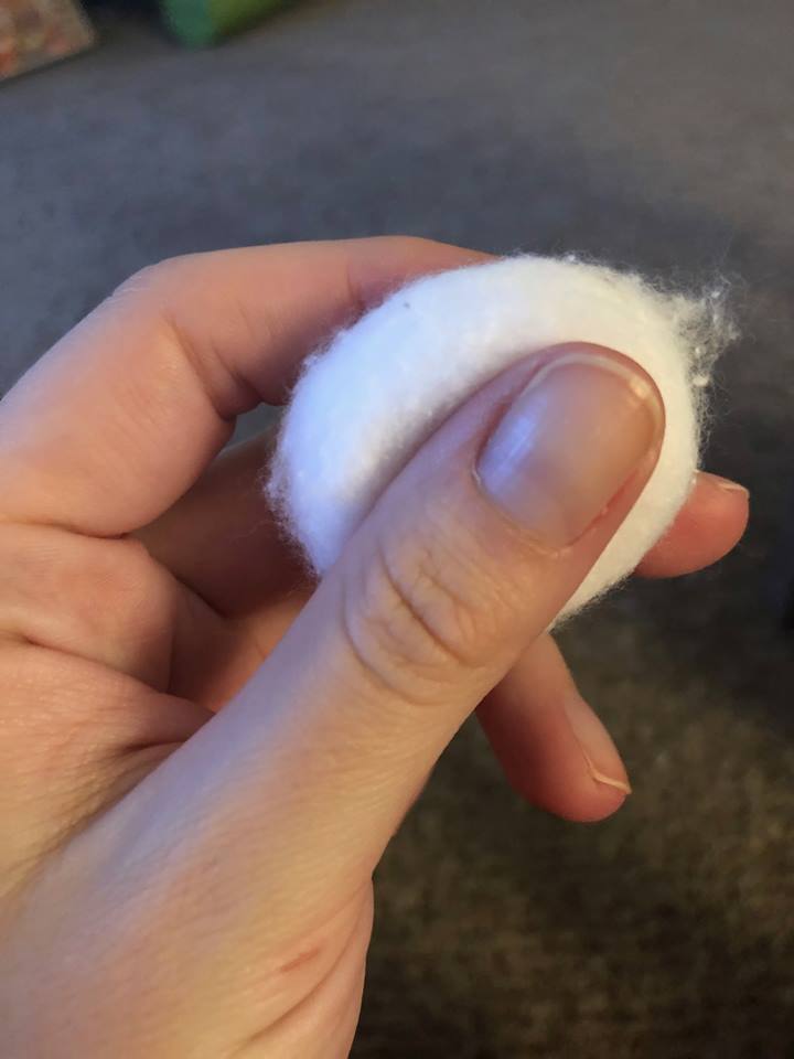 close up photo of woman holding cotton call between fingers