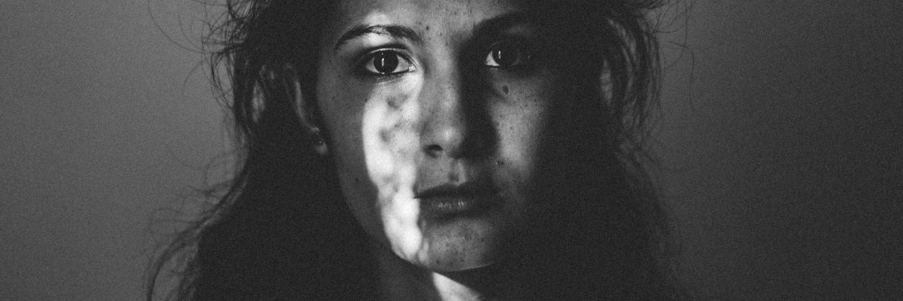 Depression Is Being Sad but Also So Much More black and white portrait photo of woman looking into camera with dark untidy hair