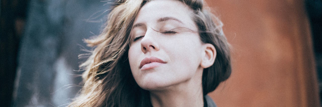 Why Do I Still Have Bad Thoughts Even in Eating Disorder Recovery? A woman with her eyes closer, looking up into the sunshine