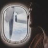 close up photo of woman looking out of window of plane