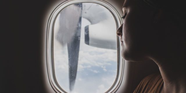 close up photo of woman looking out of window of plane