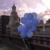 Blue balloons floating from a roof.