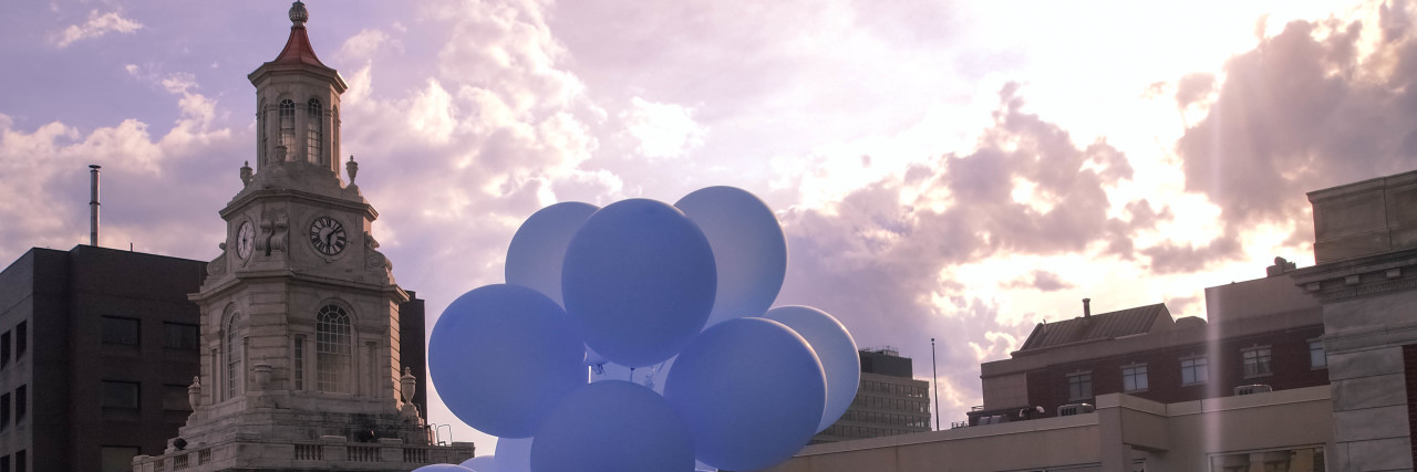 Blue balloons floating from a roof.