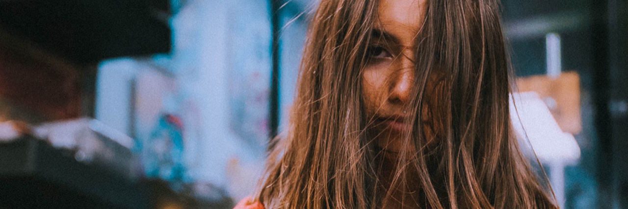 A woman crossing her arms, her brown hair in her face