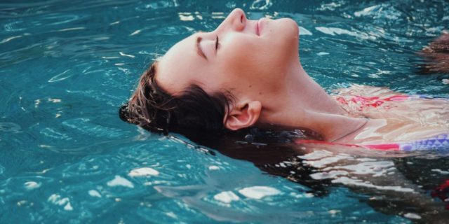 close up photo of woman relaxing in pool with smile on face