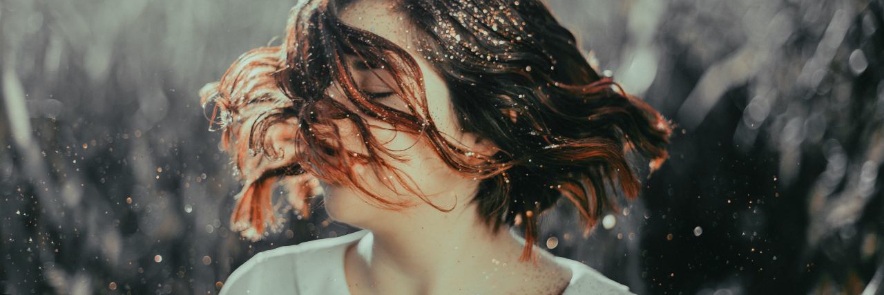 9 'Taboo' Symptoms of Bipolar Disorder A woman tossing her dark hair, which is full of glitter