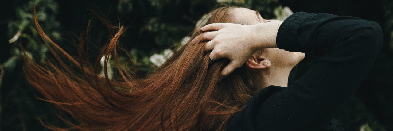 How to Care For Your Physical Health During Eating Disorder Recovery photo of woman with hands in hair in profile view standing in front of flowers
