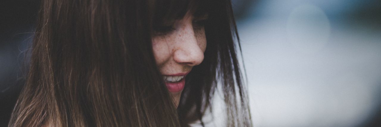 Want to Relapse in Eating Disorder Recovery close up of woman looking down and smiling with hair partially covering eyes
