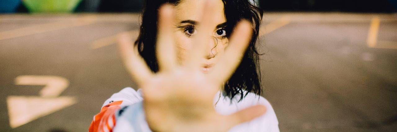 Finding Peace with Borderline Personality Disorder's Intense Emotions photo of woman looking serious into camera and holding up hand to say stop