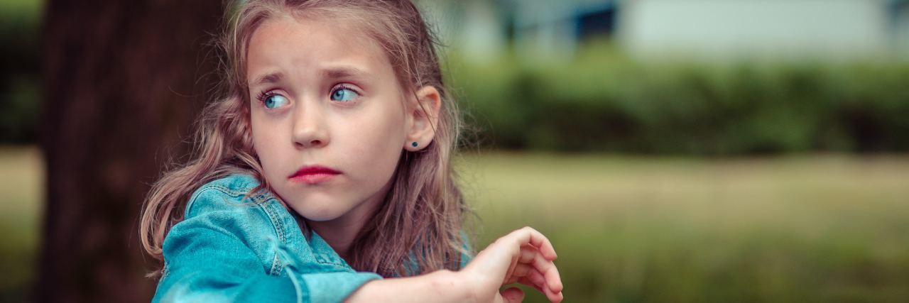 We Need to Take Childhood Suicidal Thoughts Seriously photo of young blonde girl sitting on grass and looking sad