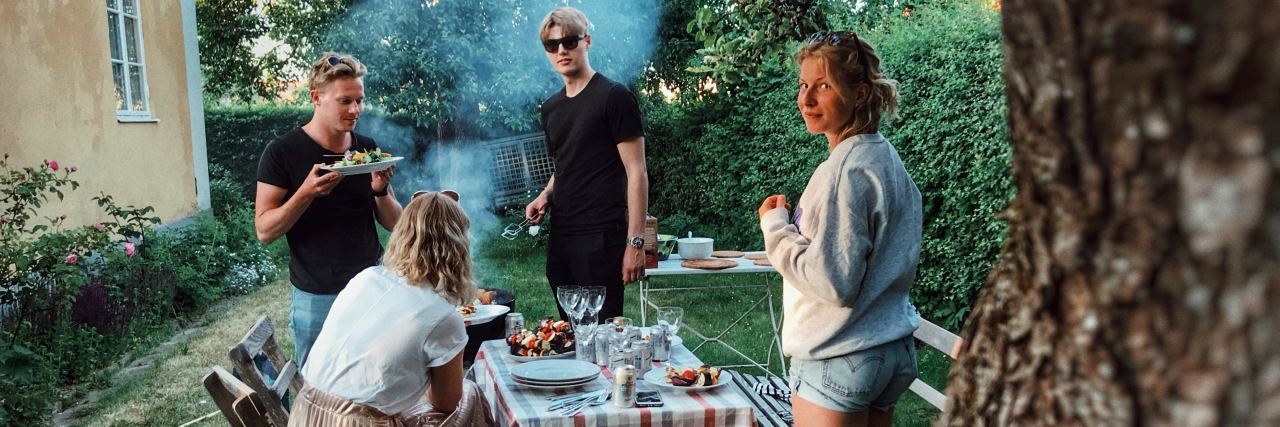 How to Support Friends With Food Allergies and Chronic Illness photo of young group of friends with food eating outdoors and one woman looking at camera