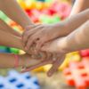 Children holding their hands together, with colorful background.