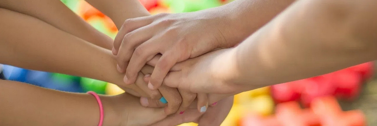 Children holding their hands together, with colorful background.